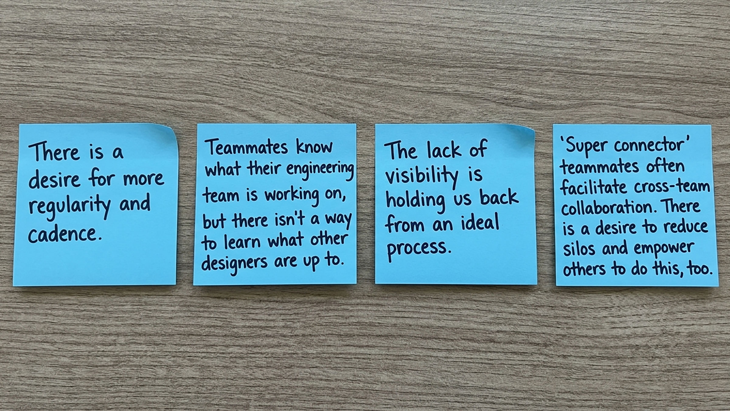 Four blue sticky notes on a desk surface, each describing a challenge with critique and visibility